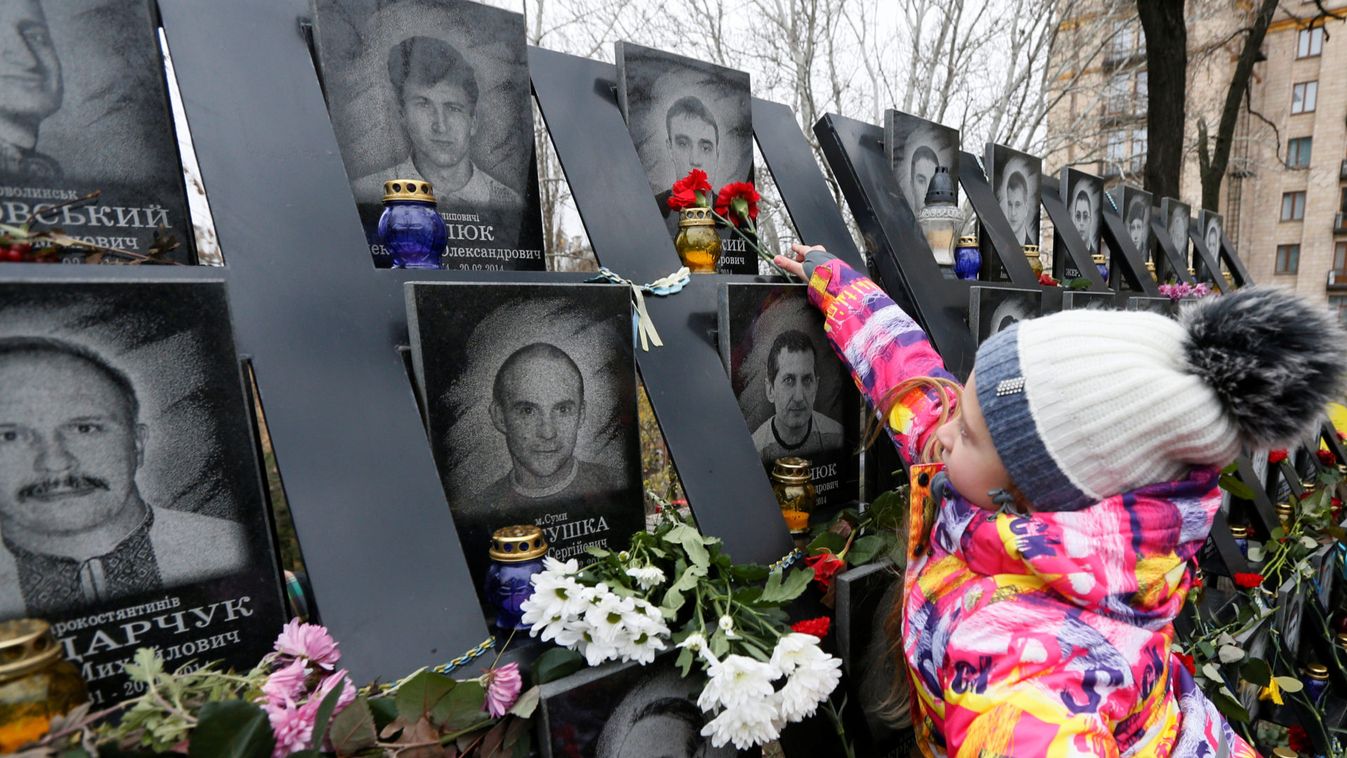A girl lays flowers during a commemoration ceremony at a monument to the so-called "Heavenly Hundred" to mark the sixth anniversary of the start of the anti-government uprising in Kiev