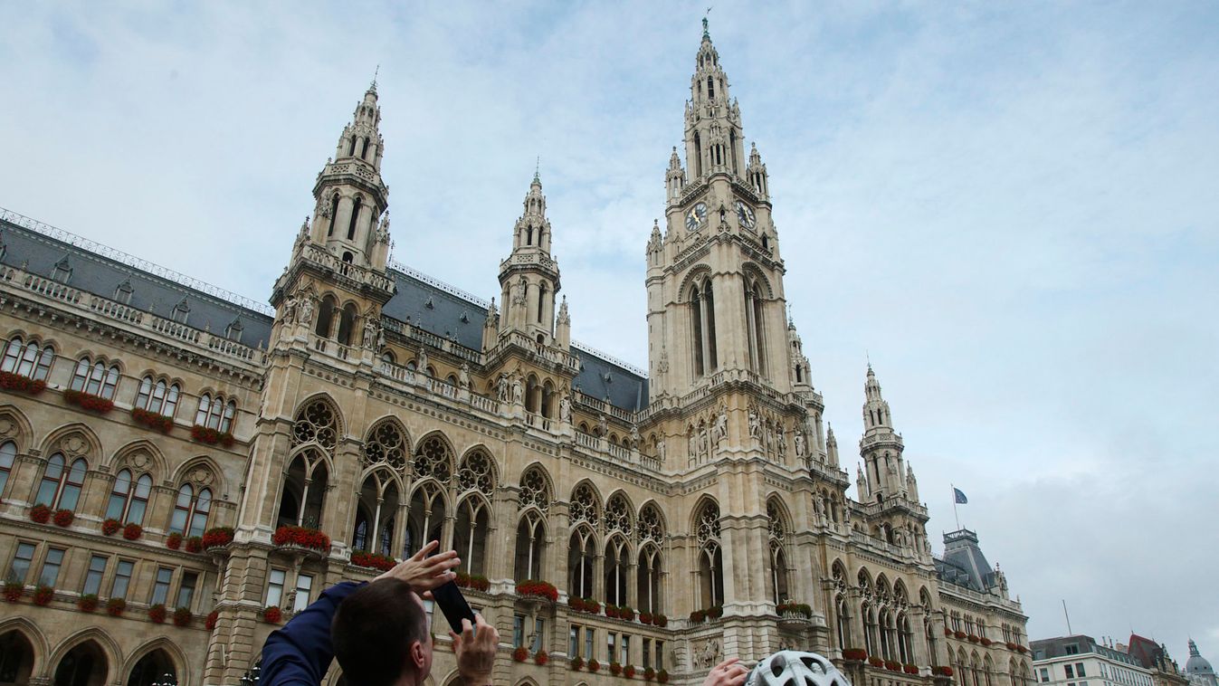 Tourists take photographs of the city hall in Vienna