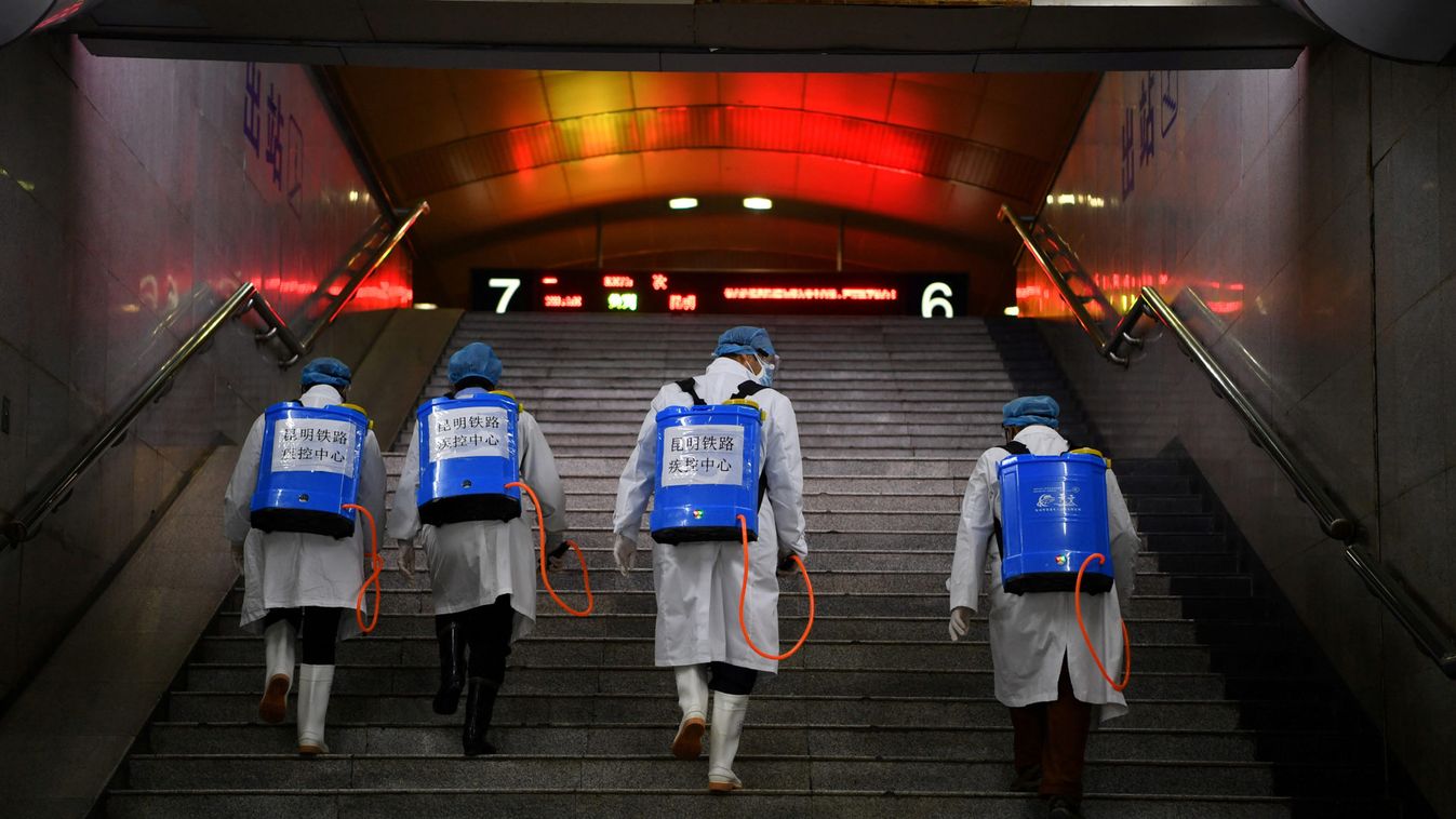 Workers with sanitizing equipment walk up a flight of stairs as they disinfect a railway station in Kunming