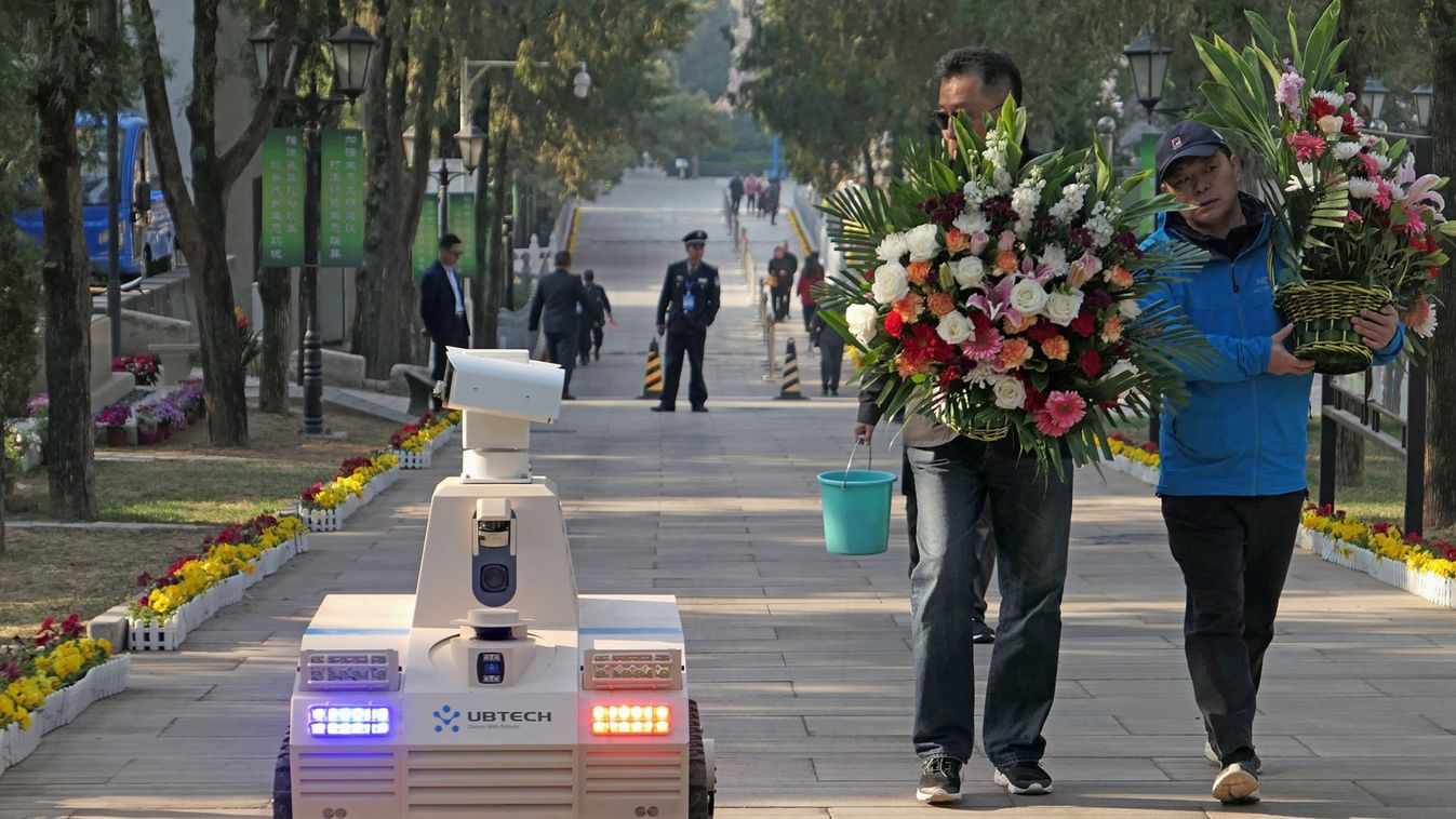 Robot patrols next to men holding flower baskets at Babaoshan Revolutionary Cemetery a day ahead of the Qingming tomb-sweeping festival in Beijing