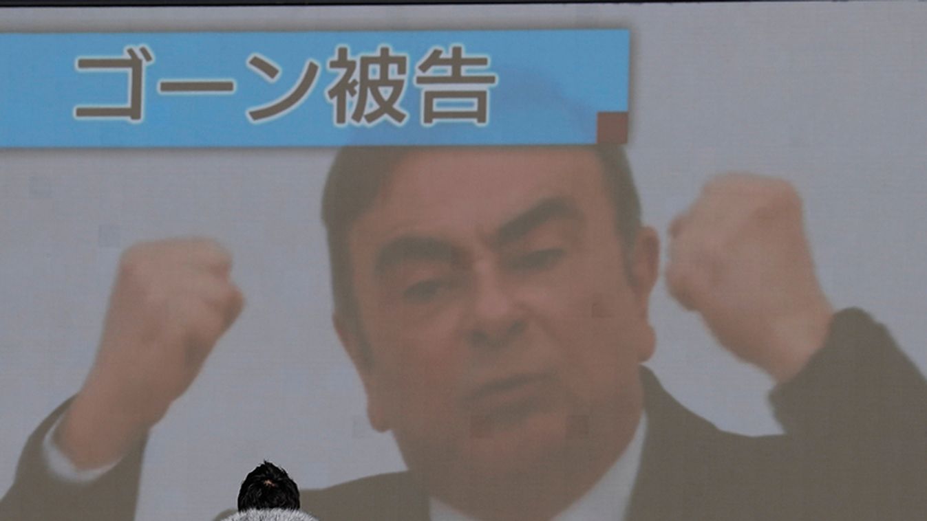 A passerby walks in front of a huge street monitor broadcasting a news conference by former Nissan chairman Carlos Ghosn in Beirut, in Tokyo, Japan