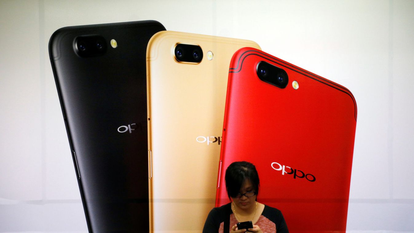 Woman uses her mobile phone next to an Oppo mobile handset advertisement in Singapore