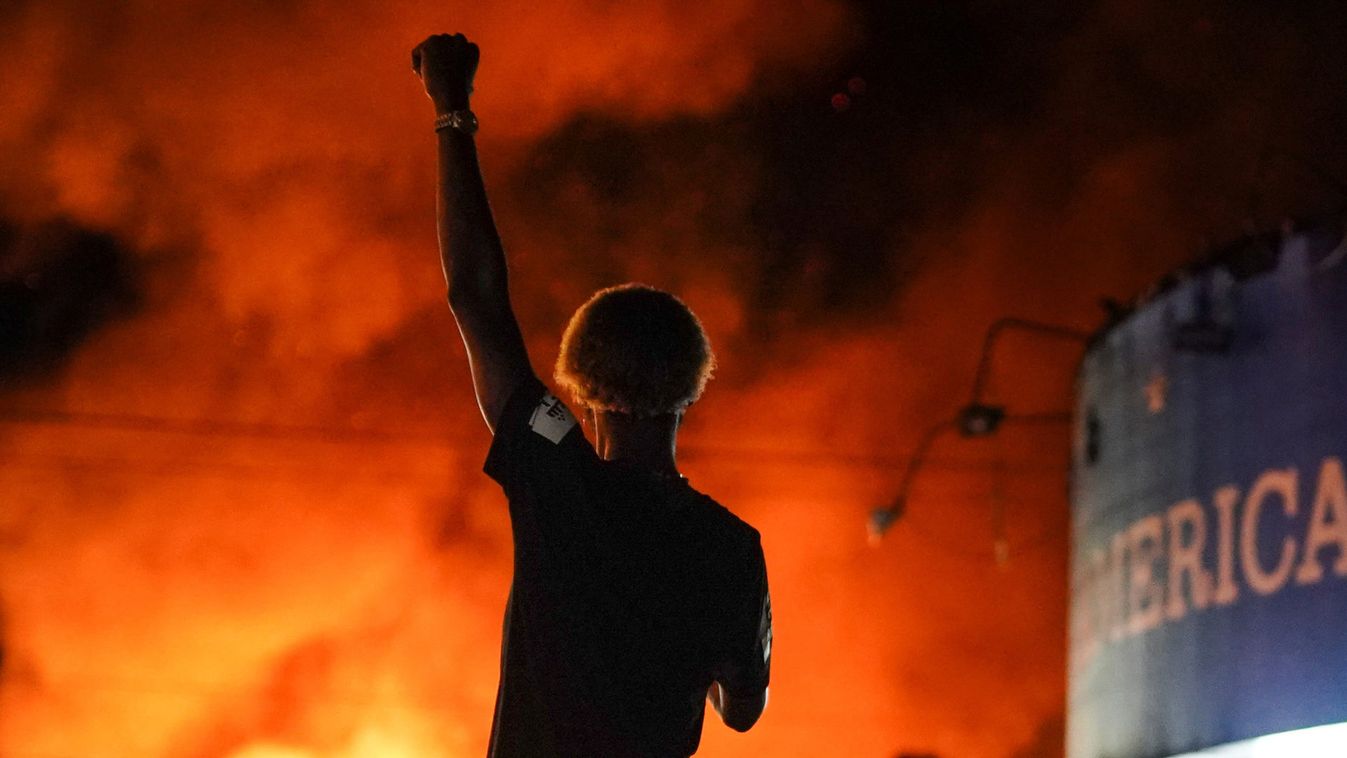 A protester watches as a Wendy’s burns following a rally against racial inequality and the police shooting death of Rayshard Brooks, in Atlanta