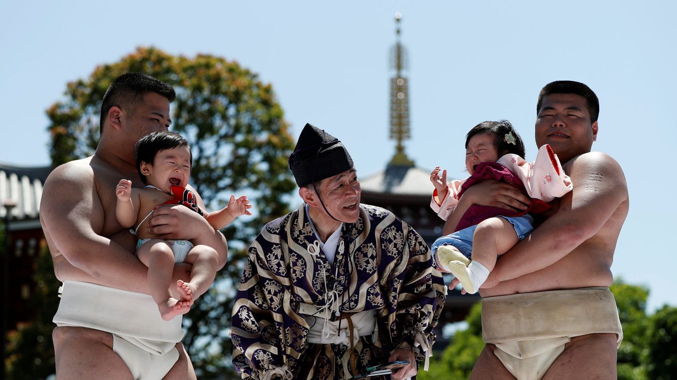 Babies cry as they are held up by amateur sumo wrestlers during a baby crying contest at Sensoji temple in Tokyo