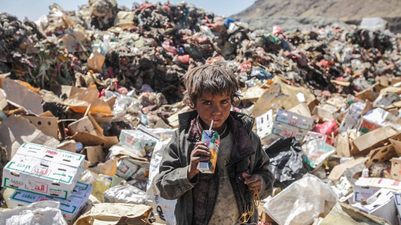 Boy drinks  expired juice on a pile of rubbish at landfill site on the outskirts of Sanaa