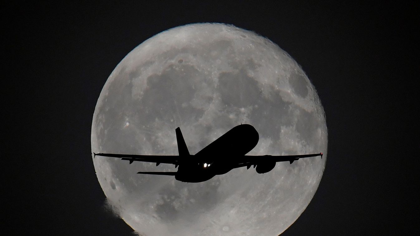 Passenger plane is seen with the moon behind as it begins its final landing approach to Heathrow Airport in London