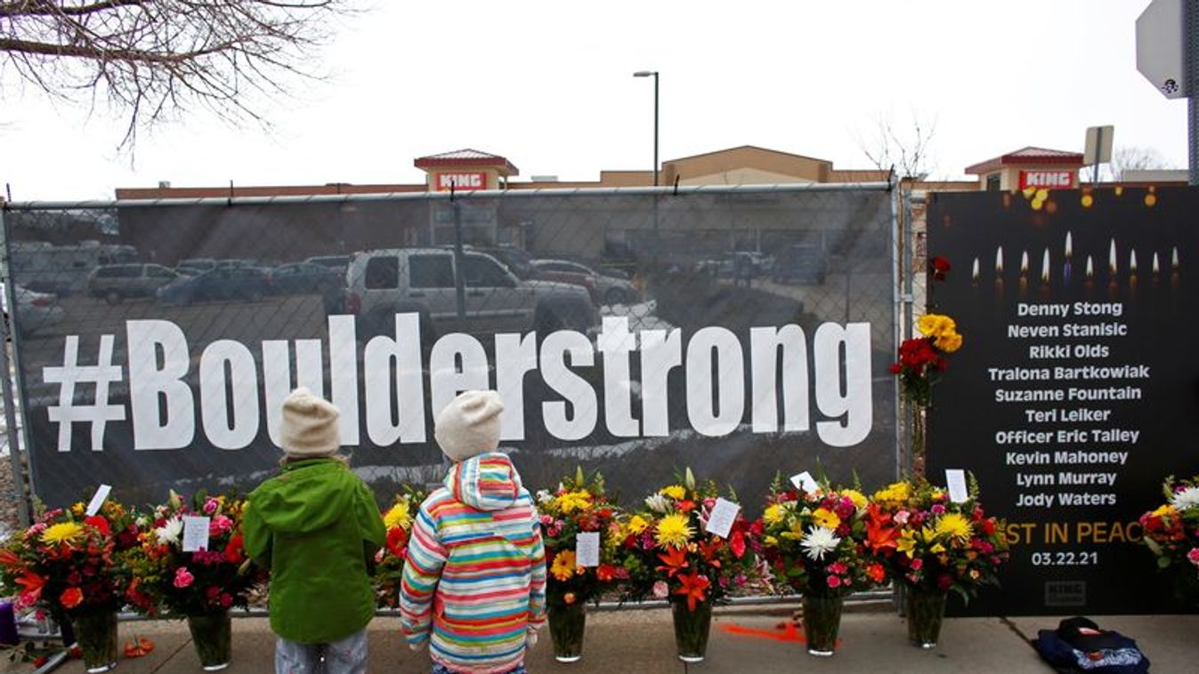 People leave flowers at the site of a mass shooting at King Soopers grocery store in Boulder