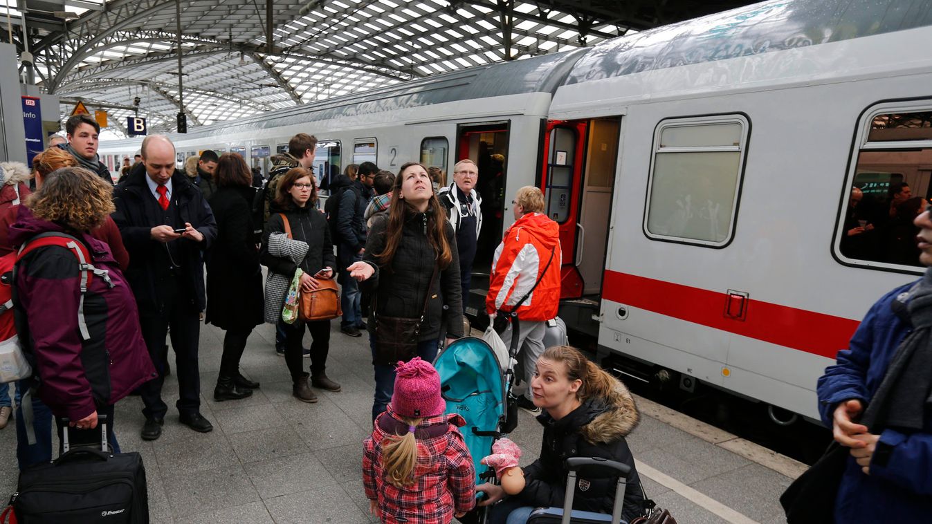 Passengers stand on a railway platform at the main train station in the western German city of Cologne