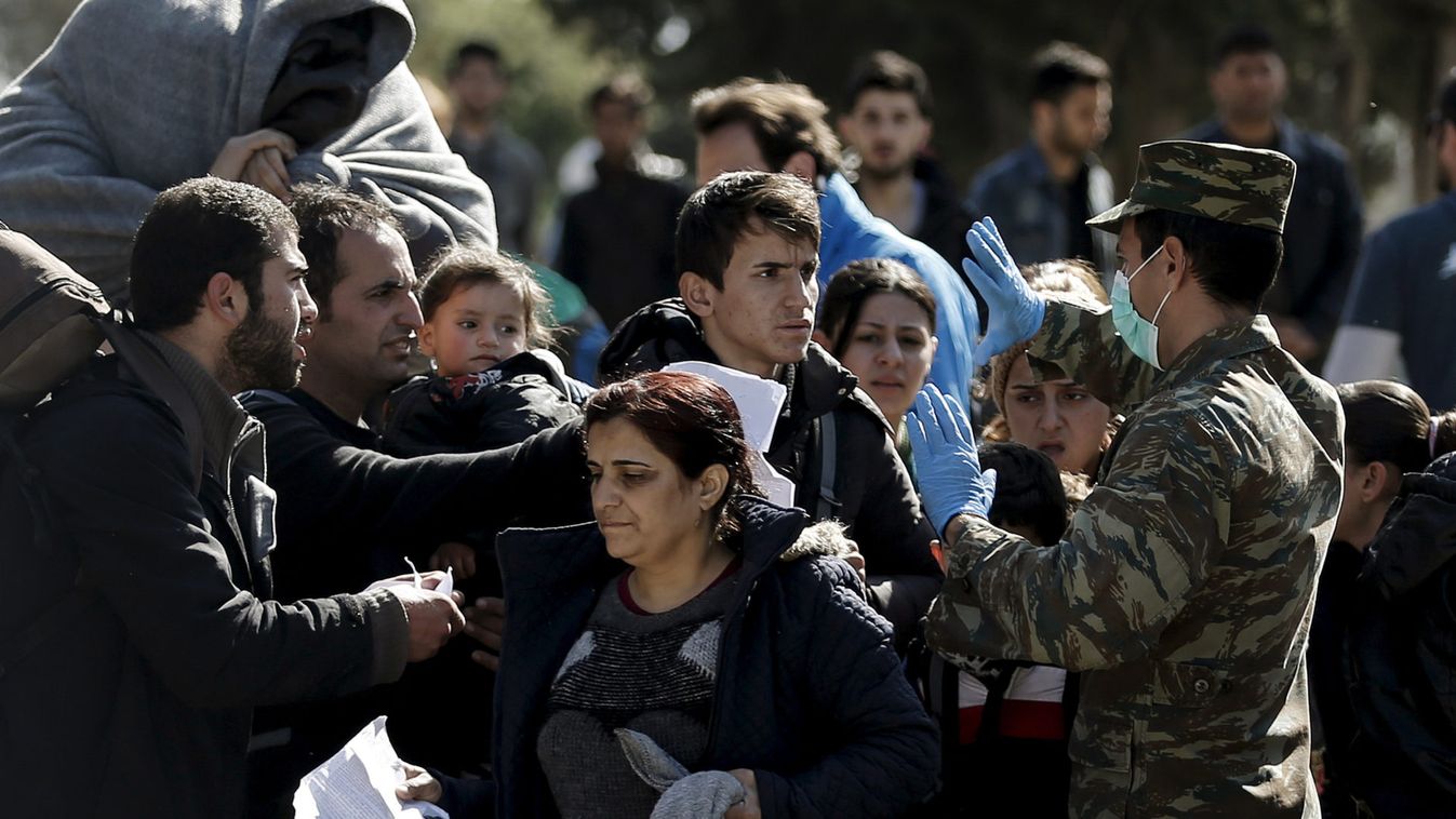 A Greek military officer checks the documents of refugees before allowing them to exit a relocation camp for refugees and travel to the Greek-Macedonian border in Schisto, near Athens