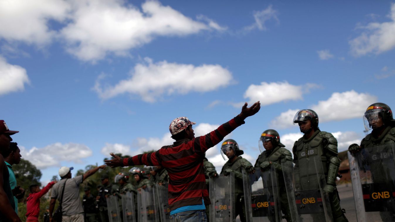 People talk with Venezuelan soldiers at the border between Venezuela and Brazil in Pacaraima