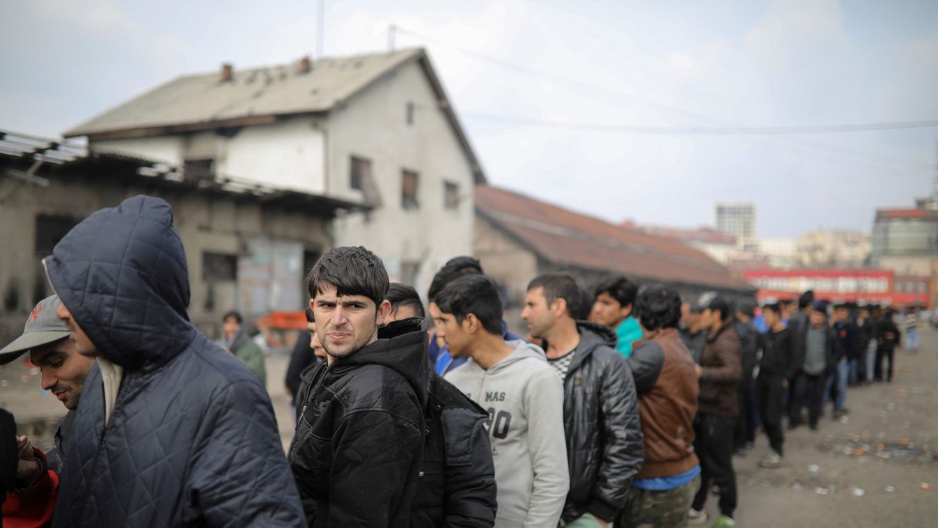 Migrants stand in line to receive free food outside a derelict customs warehouse in Belgrade