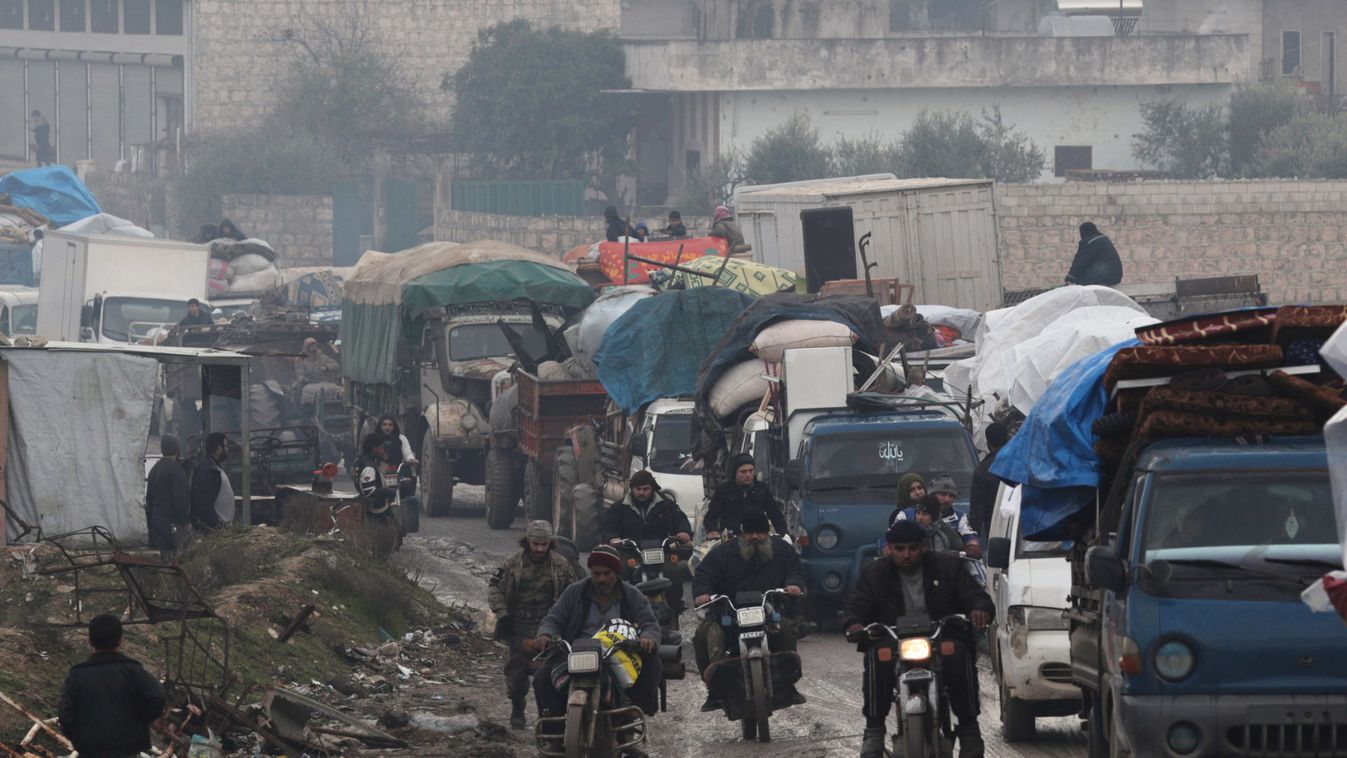 Men riding on motorbikes pass the trucks that carry belongings of displaced Syrians
