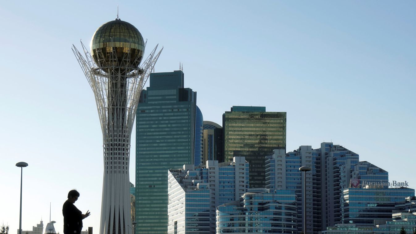 A woman is silhouetted against the backdrop of downtown with the Baiterek monument in Astana