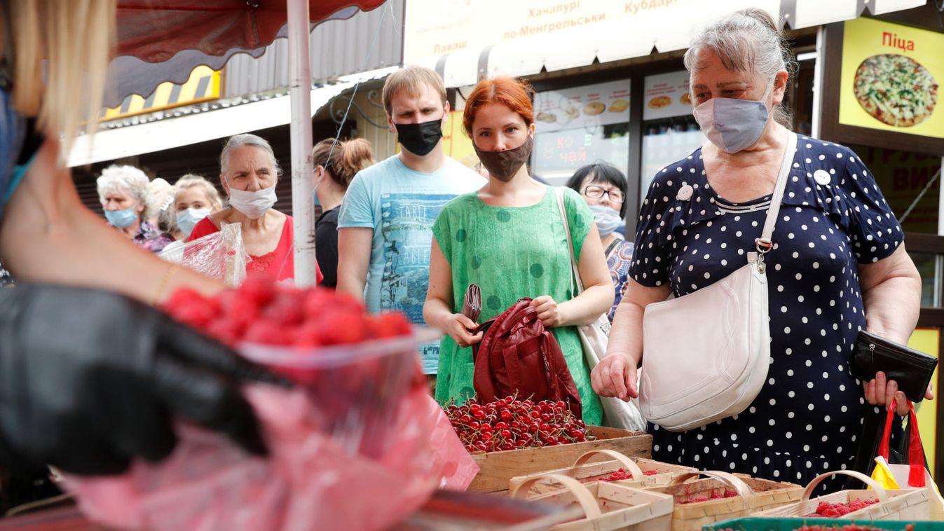 People wearing protective face masks stay in queue to buy fruits at a market in Kyiv