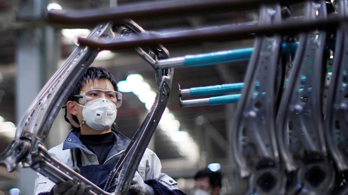 Employee wearing a face mask works on a car seat assembly line at Yanfeng Adient factory in Shanghai