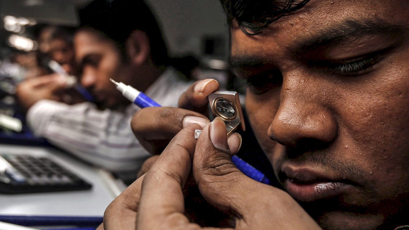 Craftsman checks the colour of a diamond at the polishing department of a diamond processing unit at Surat in Gujarat, India