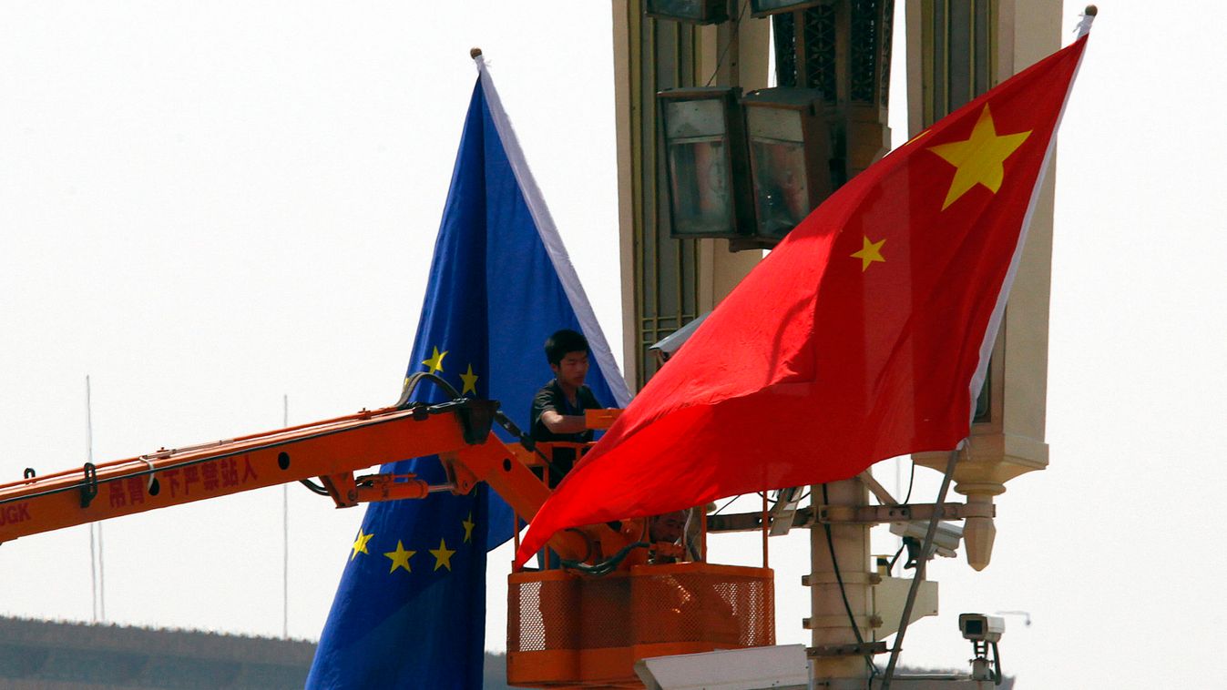 A worker on a cherry picker hangs a European Union flag next to a Chinese national flag at Beijing's Tiananmen Square in Beijing