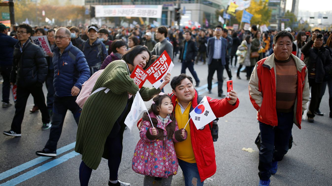 A family takes photographs during a rally demanding President Park Geun-hye to step down in central Seoul
