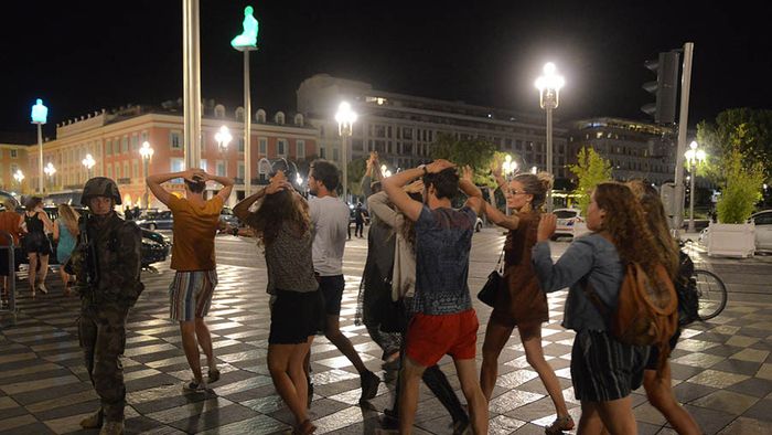 People cross the street with their hands on thier heads as a French soldier secures the area after at least 60 people were killed in Nice when a truck ran into a crowd celebrating the Bastille Day national holiday