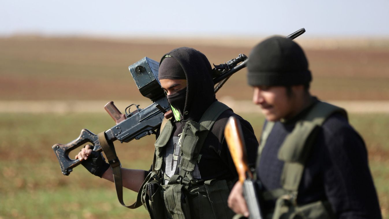 Kurdish fighters, fighting alongside the Free Syrian Army, hold weapons as they walk in northern Aleppo countryside
