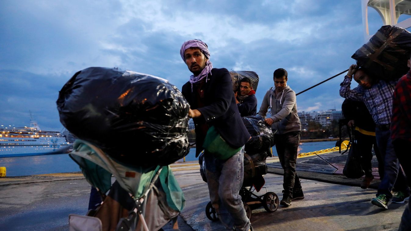 Refugees and migrants carry their luggage as they arrive on a passenger ferry from the island of Lesbos at the port of Piraeus