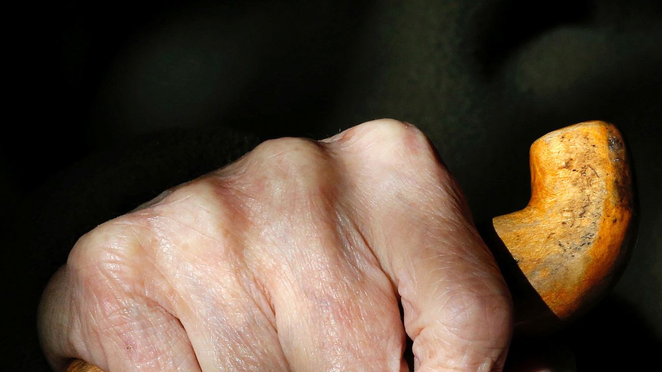 The hand of an elderly man holding his walking stick is seen at his house in Santiago