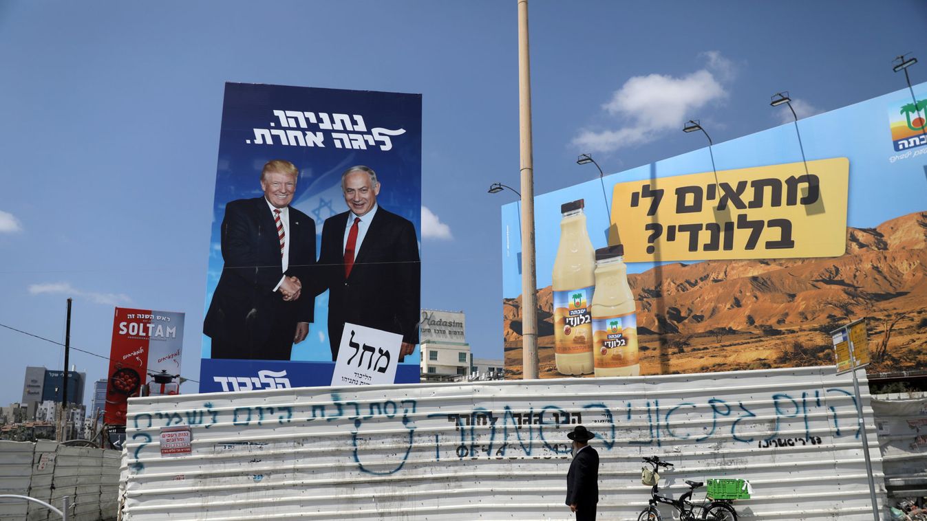 An ultra-Orthodox Jewish man stands next to a Likud party election campaign banner depicting Israeli Prime Minister Benjamin Netanyahu and U.S. President Donald Trump in Bnei Brak, Israel