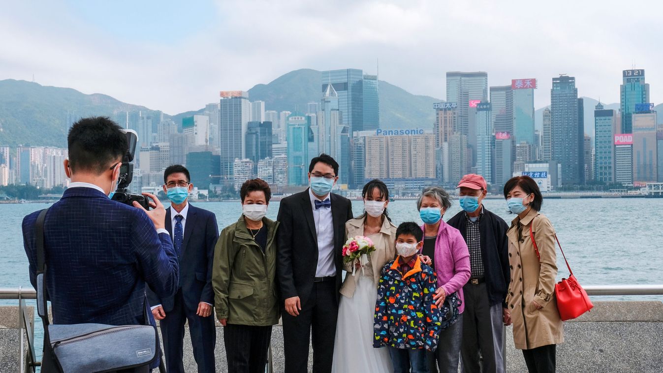 Newly-wed couple wear protective masks as they take wedding photos with family after marriage registration, following the outbreak of the new coronavirus, at Tsim Sha Tsui district in Hong Kong