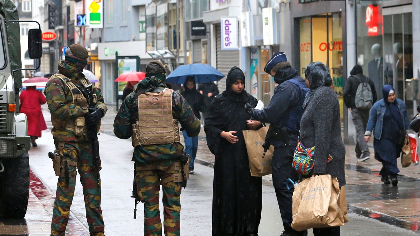 Belgian soldiers and a police officer control documents of a woman in a shopping street in central Brussels after security was tightened in Belgium following the fatal attacks in Paris