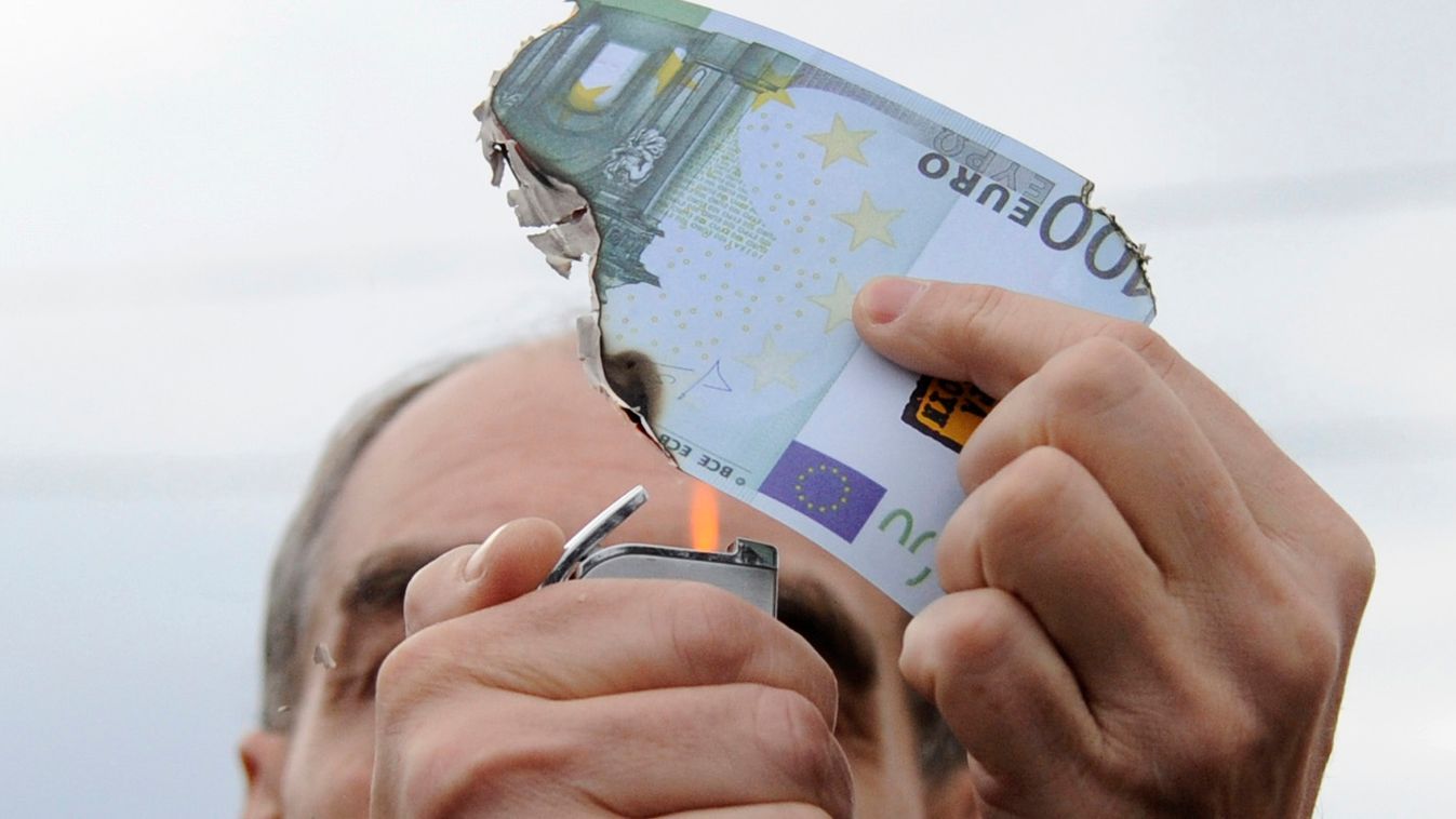 A protester burns a fake one hundred Euro banknote during a demonstration against a new package of tax hikes and reforms in Athen