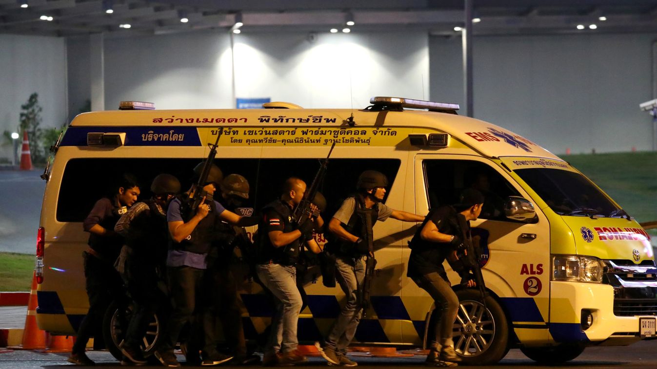 Thai security forces take cover behind an ambulance as they chase a shooter hidden in a shopping mall after a mass shooting in front of the Terminal 21, in Nakhon Ratchasima, Thailand