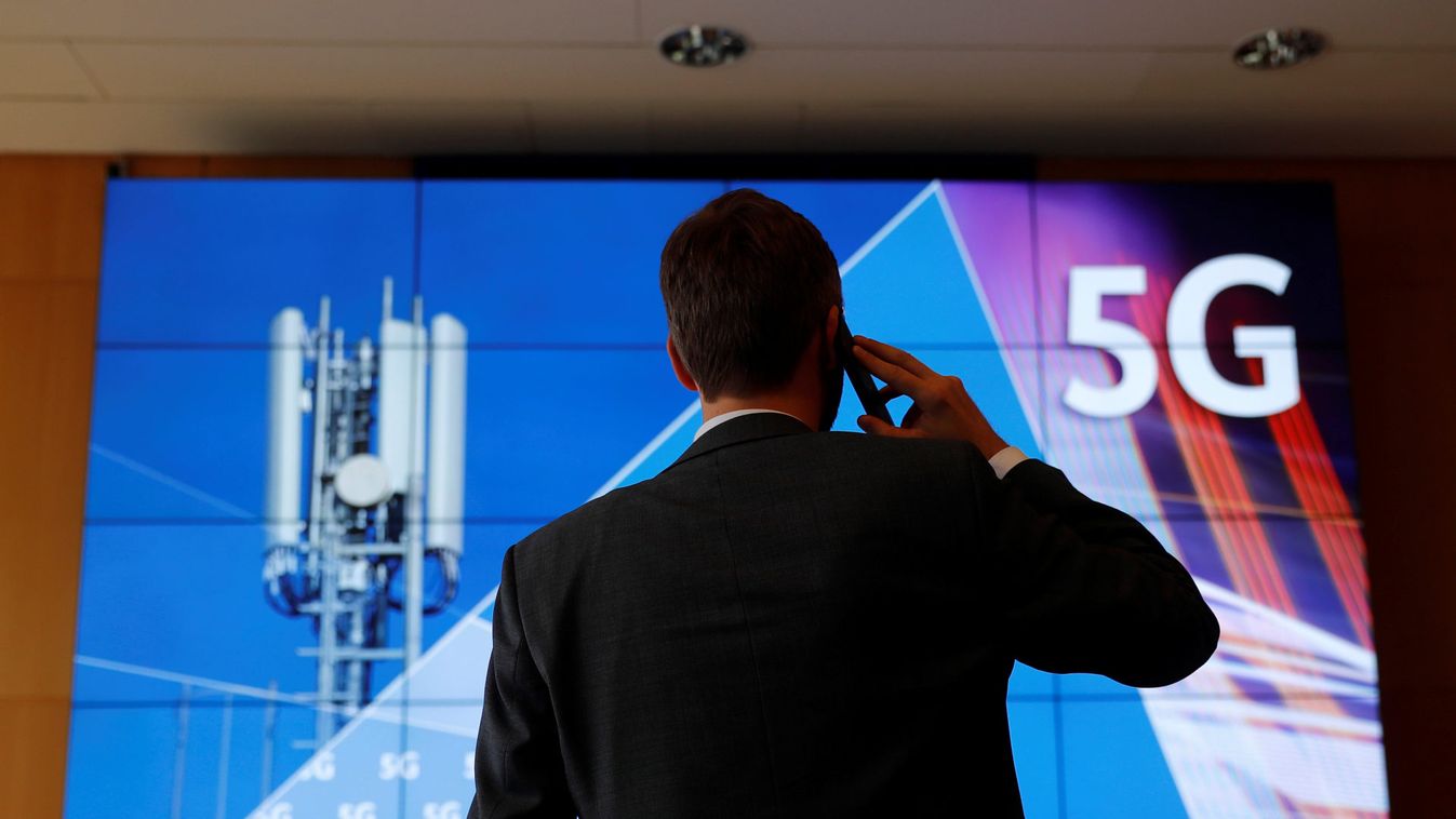 An employee of Germany's Federal Network Agency (Bundesnetzagentur) uses his mobile phone in front of a screen set up for the auction of spectrum for 5G services at the Bundesnetzagentur headquarters in Mainz