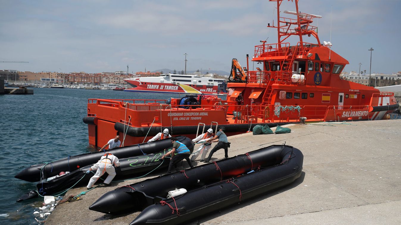 A Spanish civil guard, a member of Frontex and rescuers move a dinghy of migrants after arriving on a rescue boat at the port of Tarifa