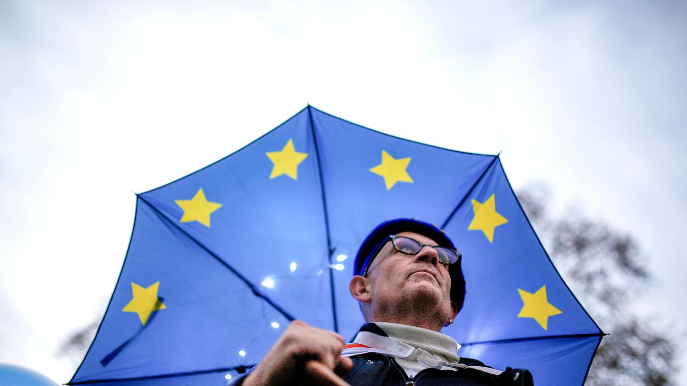 An anti-Brexit demonstrator stands under an EU flag umbrella outside the Houses of Parliament in London