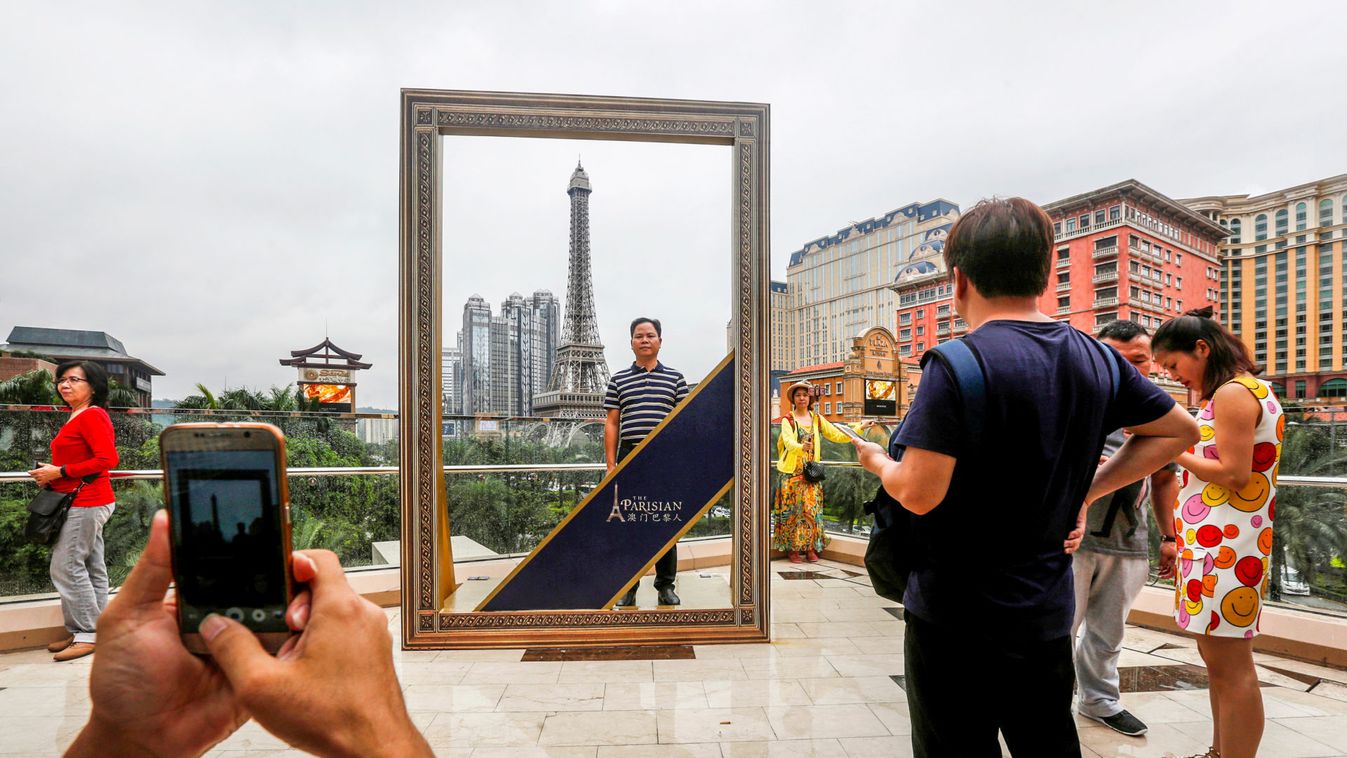 Visitors take photos in front of a scale replica of Eiffel Tower as part of the Parisian Macao in Macau