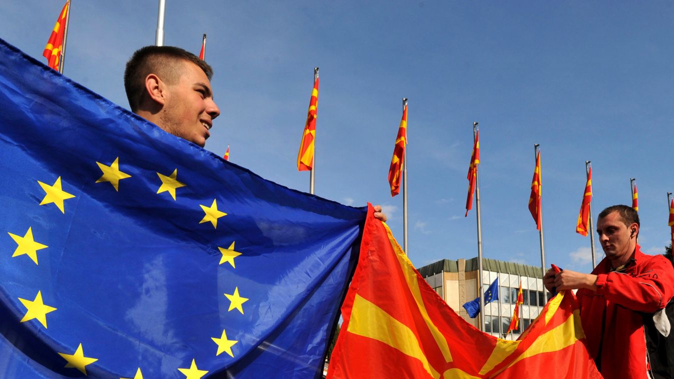Men wave E.U, and Macedonian flags in front of the Macedonian Government building in Skopje