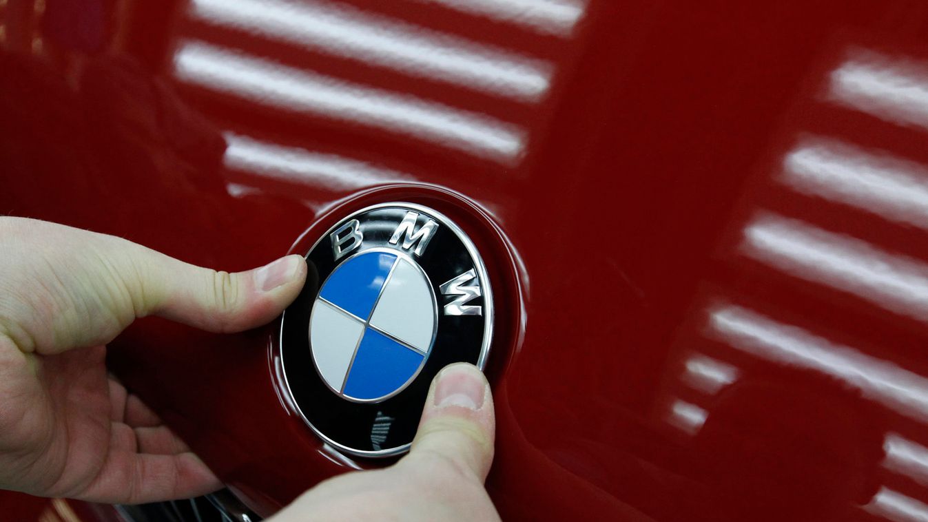 A worker attaches emblem to bonnet of BMW car at car maker's plant in Leipzig