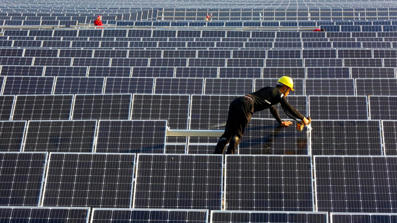 Man works on solar panels at a solar power plant of China Huaneng Group in Huaiyin