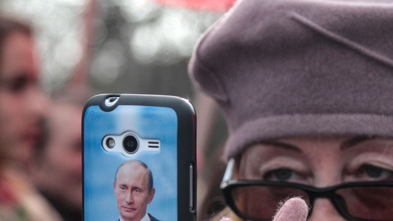 A portrait of Russian President Putin is seen on a cover of a woman's phone as she takes pictures during celebrations of the Russian national holiday - Defender of the Fatherland Day in Sevastopol