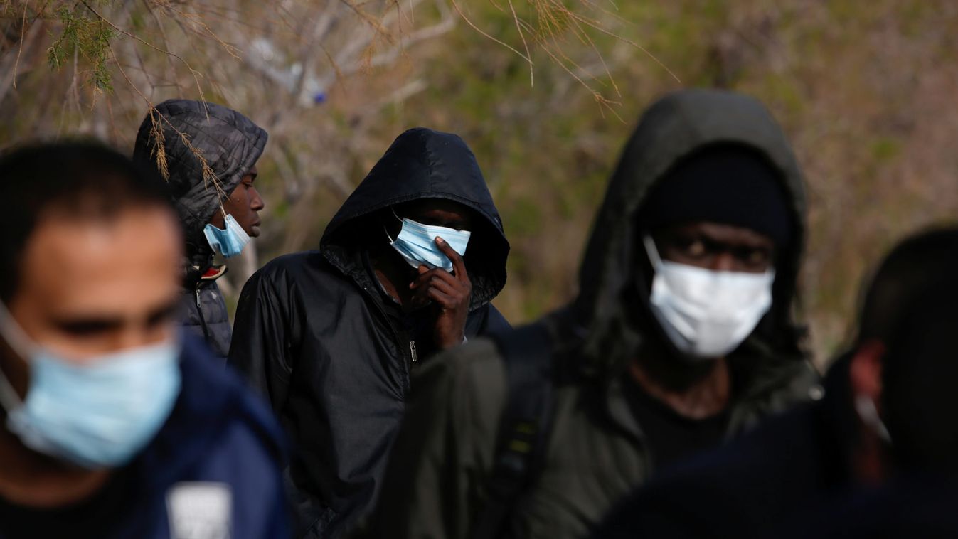 Migrants from sub-saharan African countries wear protective face masks handed over by Greek coast guard officers following their arrival on a dinghy near the city of Mytilene, after crossing part of the Aegean Sea from Turkey to the island of Lesbos