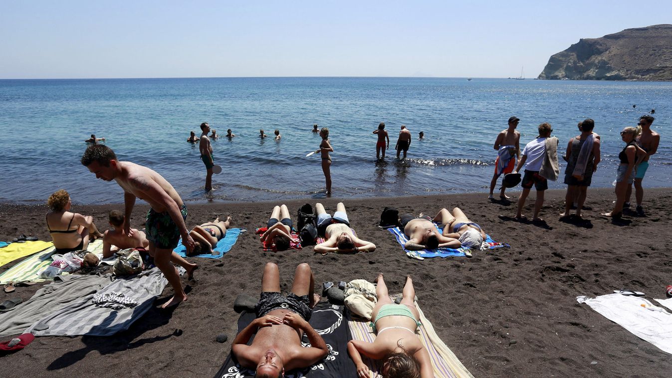 Tourists sunbathe on the Red Beach on the Greek island of Santorini, Greece
