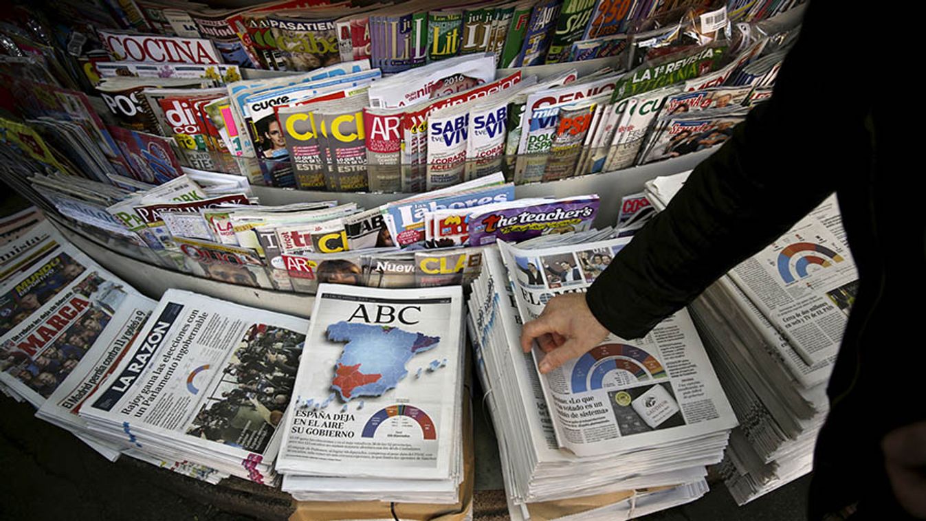 A man takes a newspaper at a kiosk in central Madrid, Spain