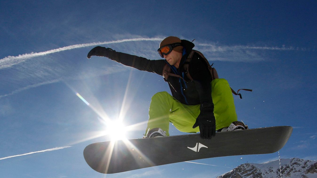 Snowboarder performs jump in front of Alps during winter season opening day at Zugspitze