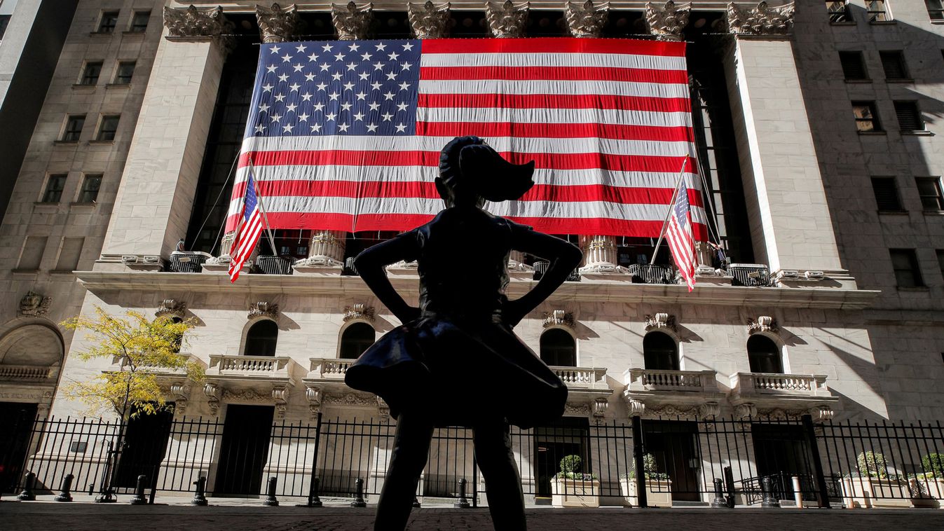 The Fearless Girl statue is seen as the  U.S. flag covers the front facade of the NYSE in New York