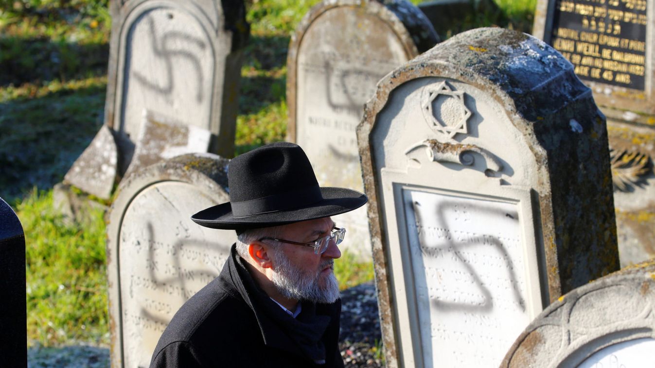 A man walks past graves desecrated with swastikas at the Jewish cemetery in Westhoffen
