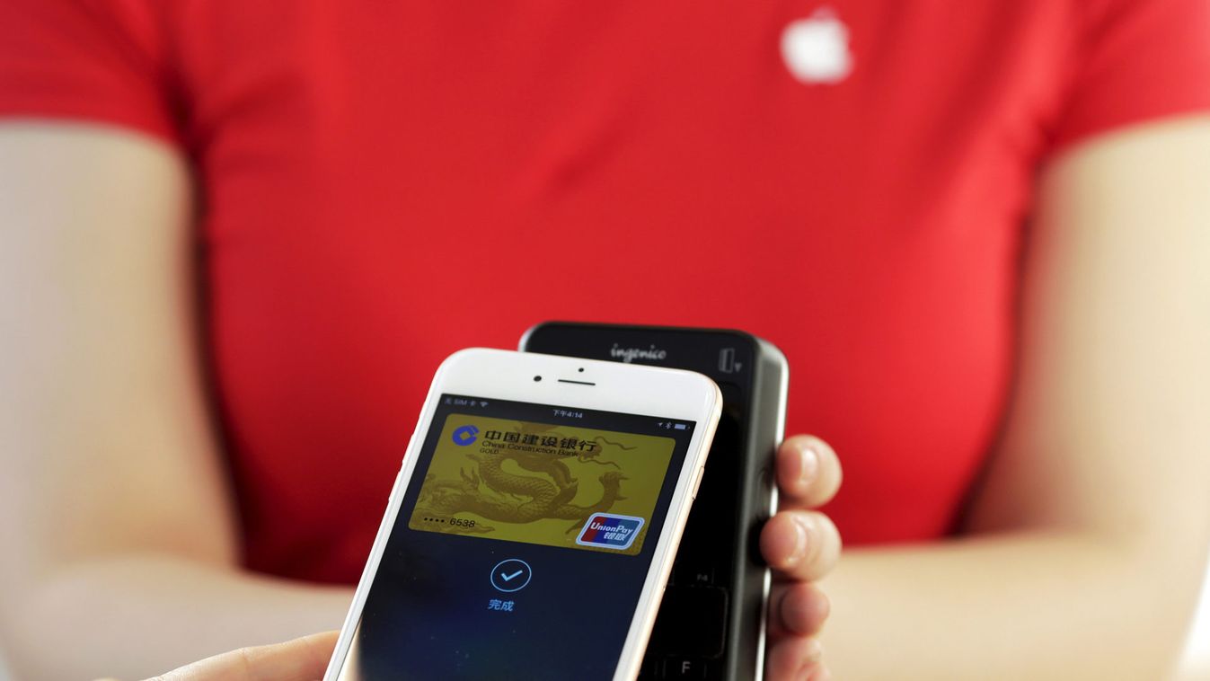 Employees use an Apple iPhone to demonstrate the Apple Pay service in Beijing
