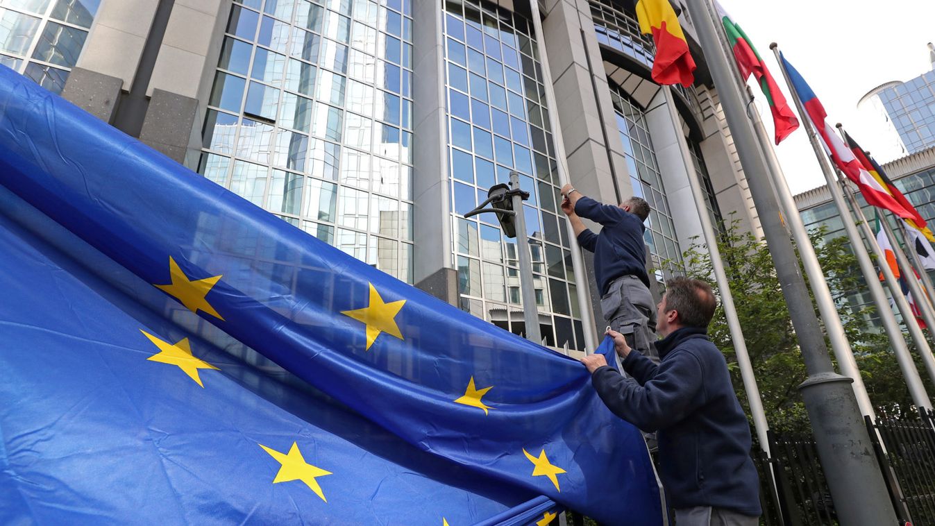Workers adjust a European flag outside the EU Parliament ahead of the EU elections in Brussels