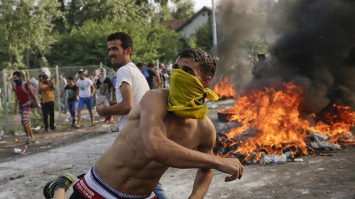 Migrants protest as Hungarian riot police fires tear gas and water cannon at the border crossing with Serbia in Roszke