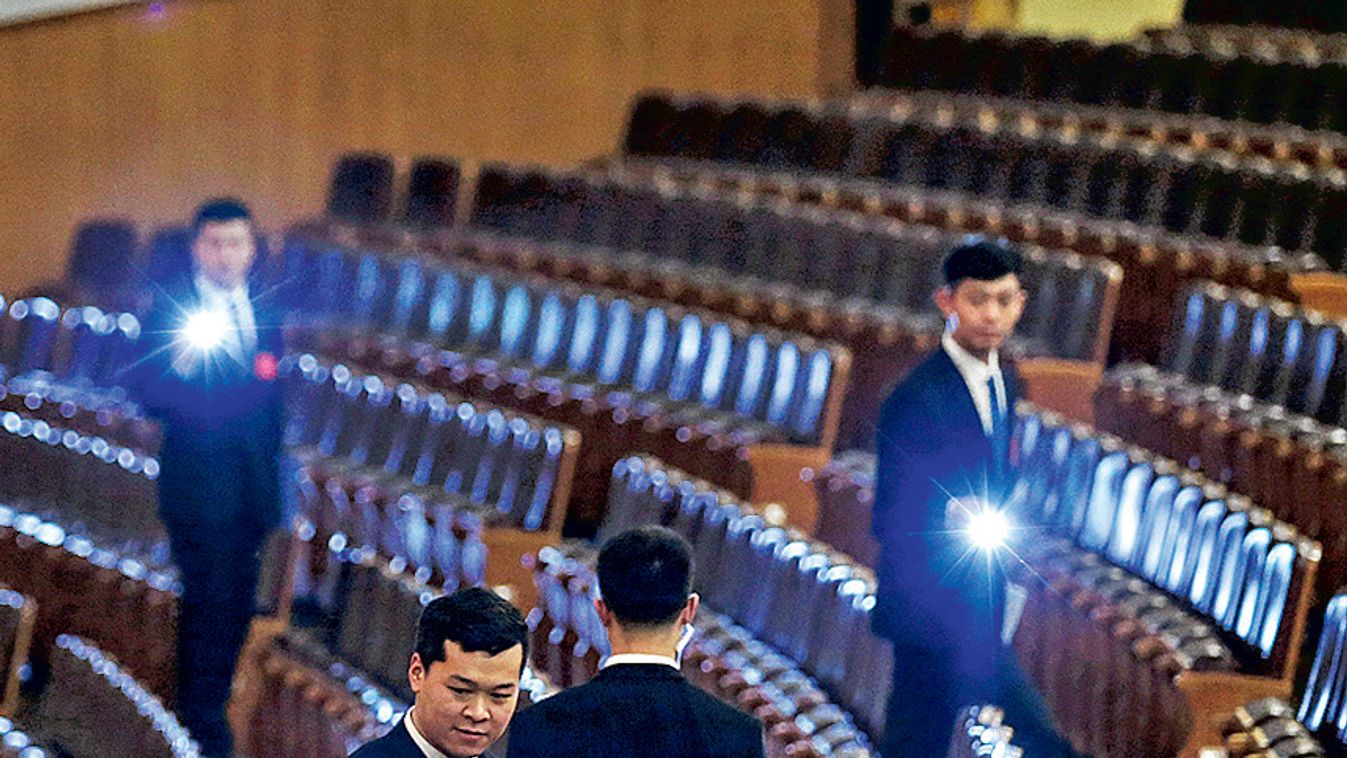 Security personnel check the seats with torches at the end of the opening session of the National People's Congress (NPC) at the Great Hall of the People in Beijing