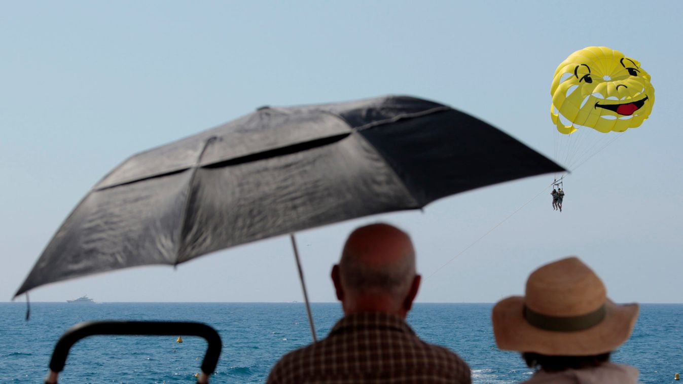 Two elderly people look at a parascending during a sunny summer day in Nice
